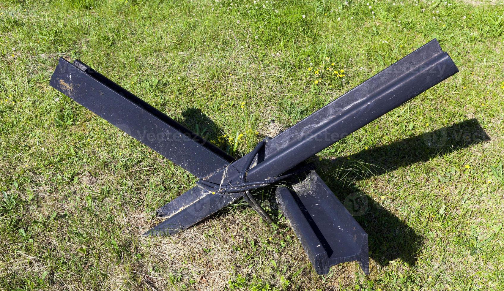 anti tank metal fortifications and hedgehogs on green grass photo