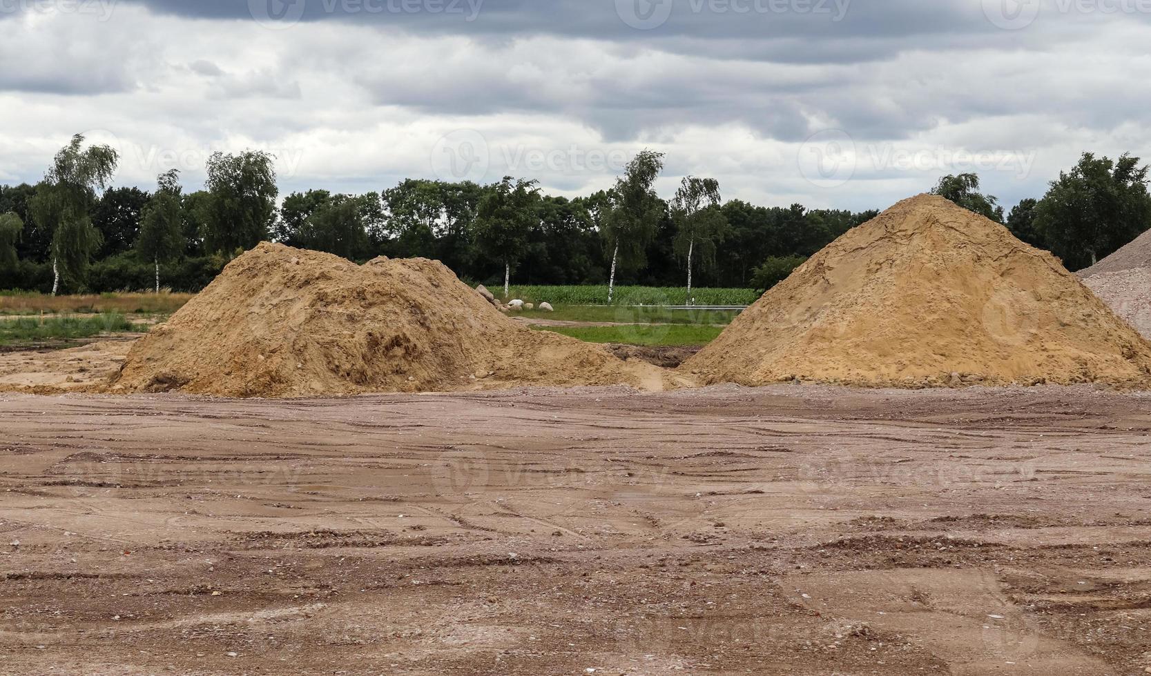 View into a gravel pit with piles of sand and some tire tracks photo