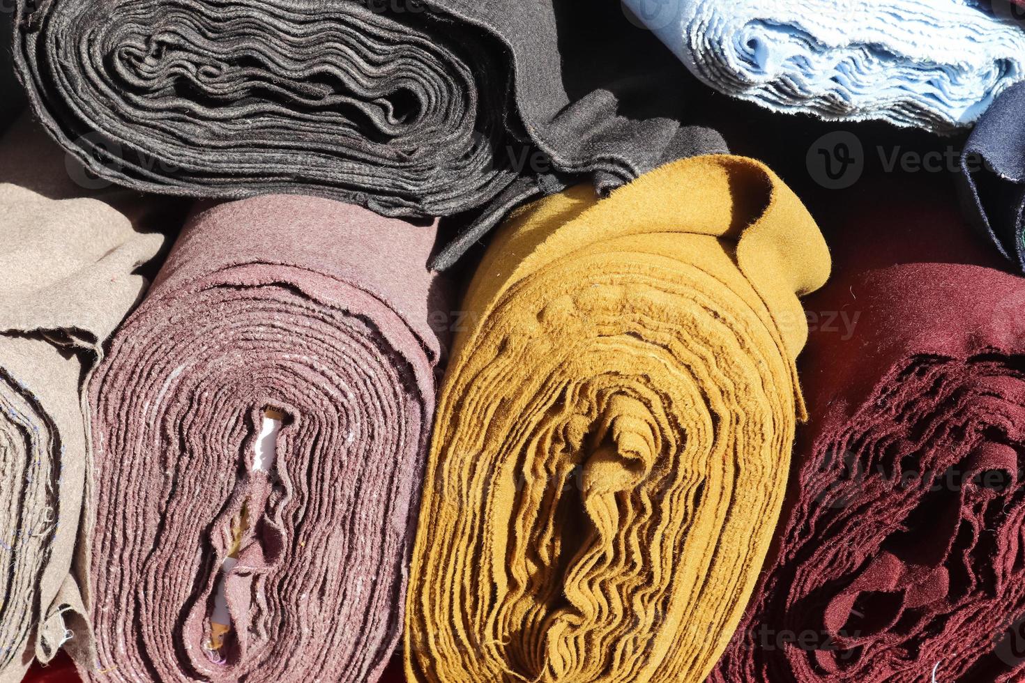Close up view on rolled samples of cloth and fabrics in different colors found at a fabrics market.. photo