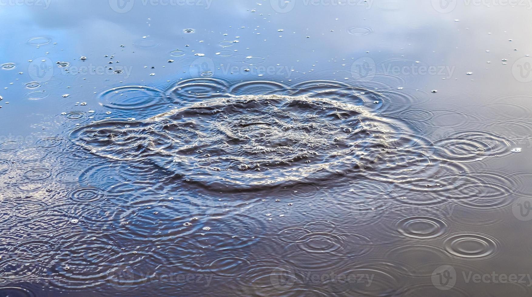 Beautiful water at a lake with splashing water and ripples on the surface with clouds and blue sky reflections photo