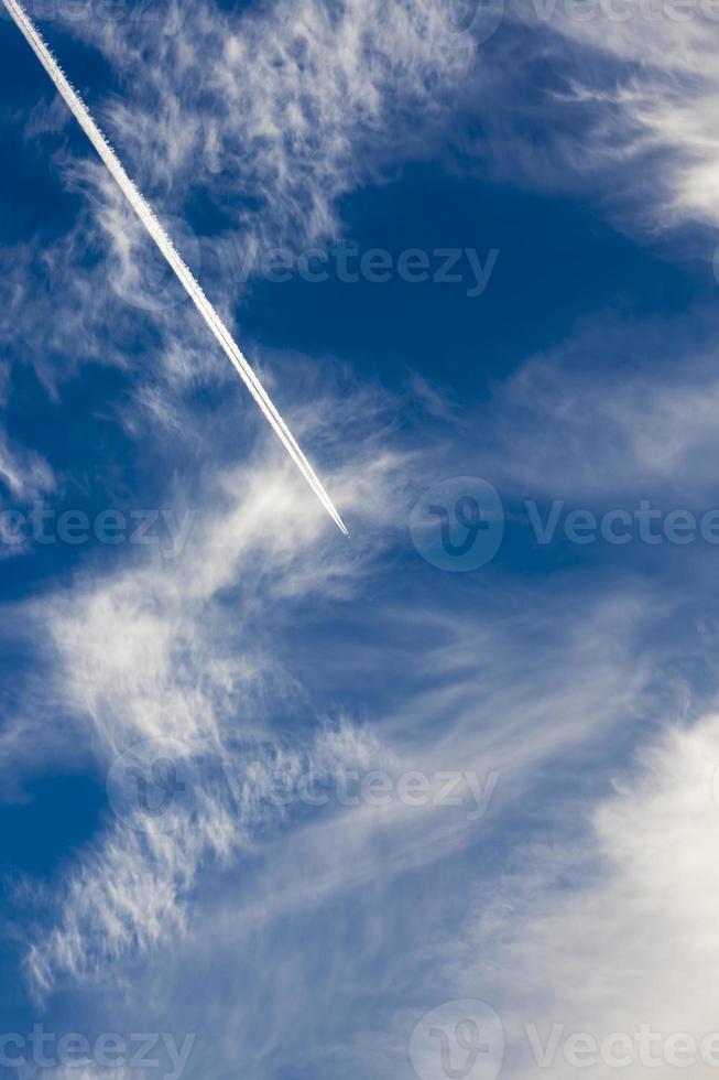 un avión volando a través de un cielo nublado azul foto