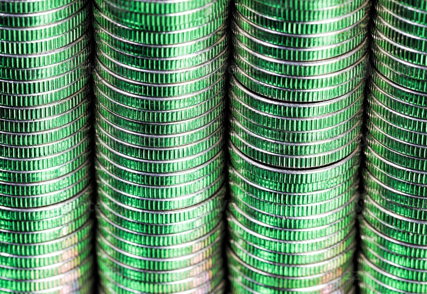 many round metal coins of silver color illuminated in green photo
