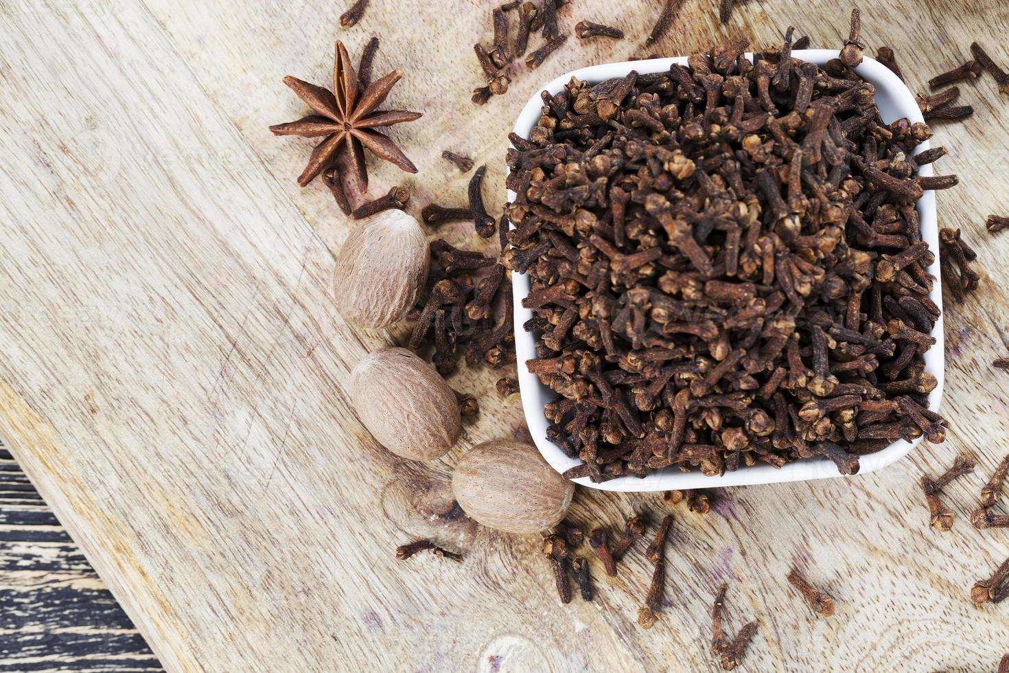 spices of cloves scattered on an old wooden table photo