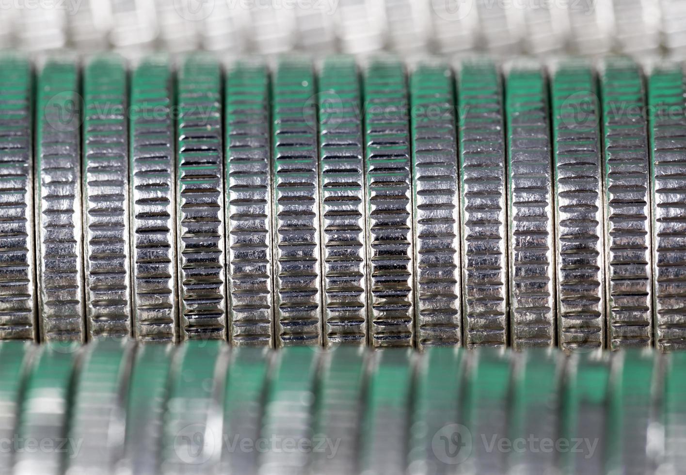 many round metal coins of silver color illuminated in green photo