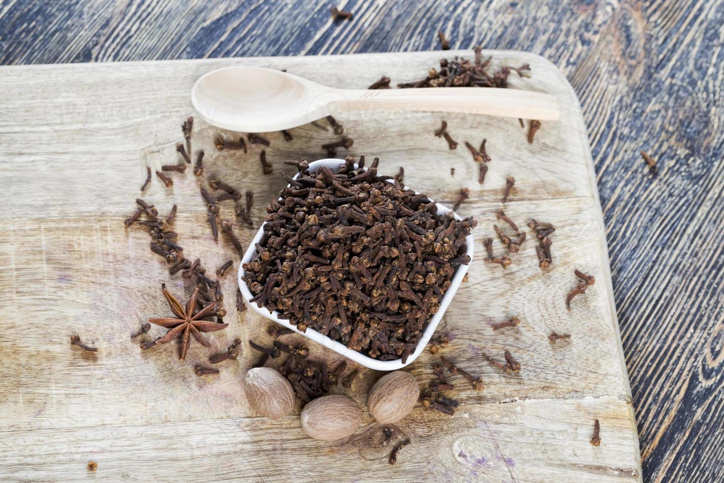 spices of cloves scattered on an old wooden table photo