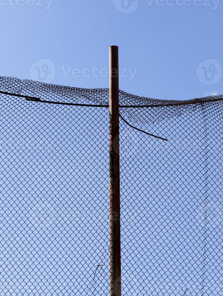 old wire fence made of thin wire against the blue sky photo