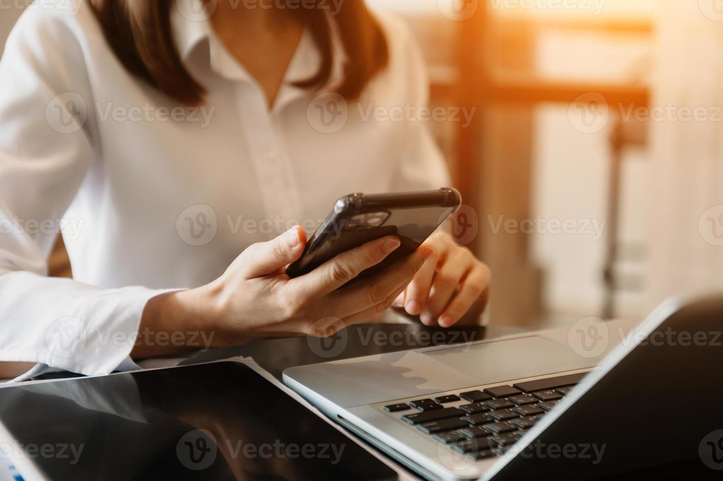 Businessman hand using smart phone laptop and tablet with social network diagram on desk as concept at office photo