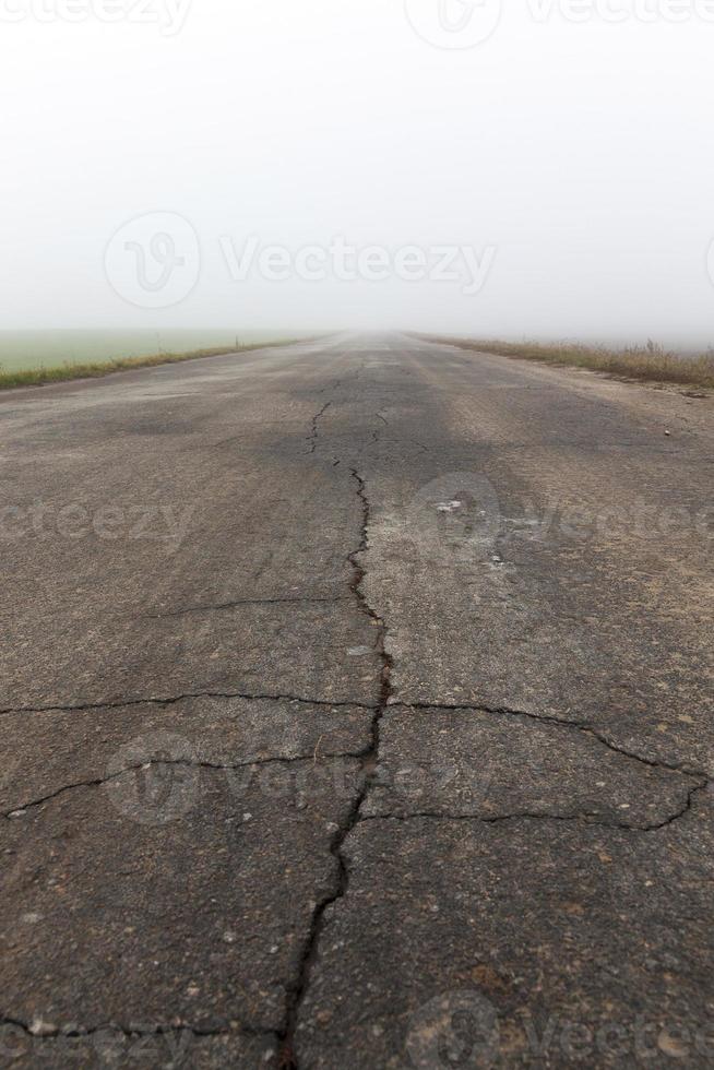 asphalted road, autumn and fog closeup. Small depth of field. In the background is seen the sky photo