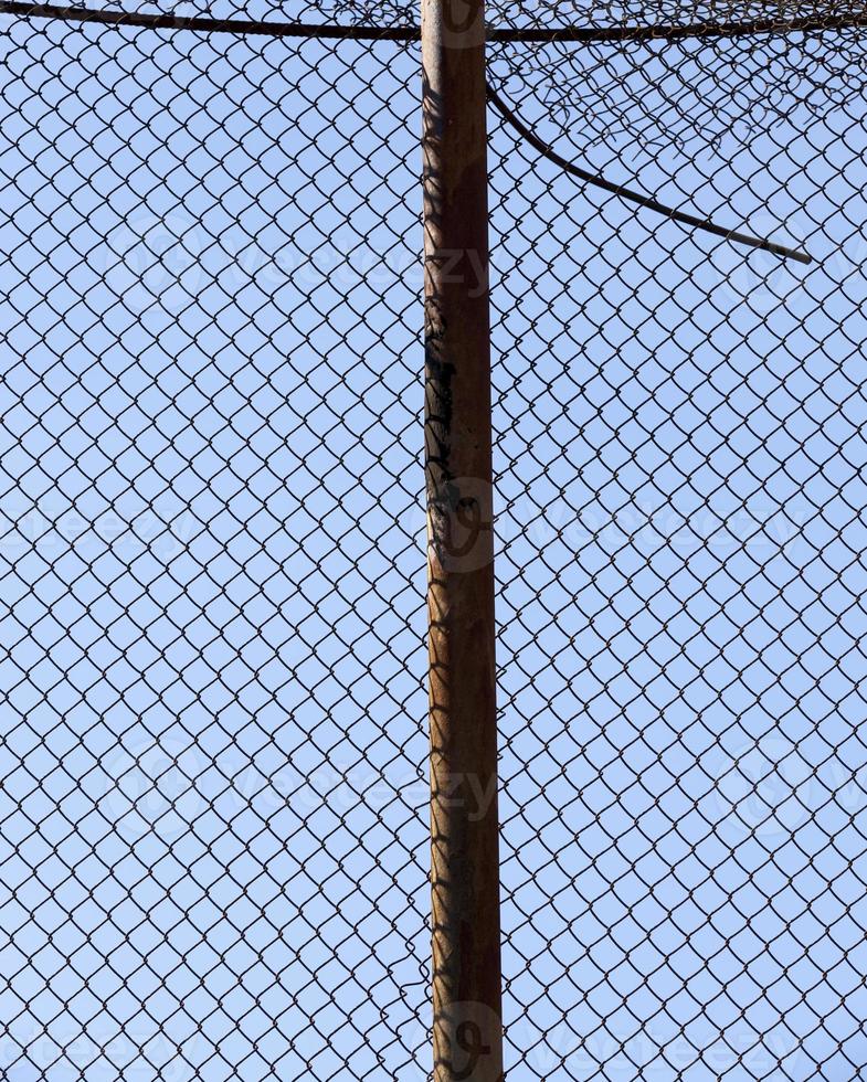old wire fence made of thin wire against the blue sky photo