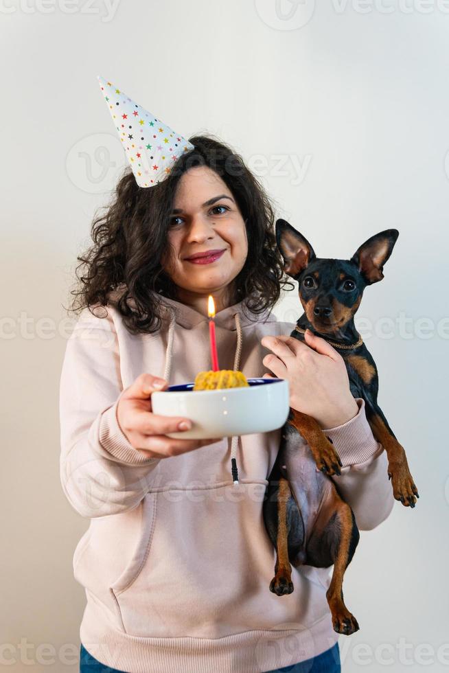 niña feliz dando pastel casero a su perro, en el interior foto