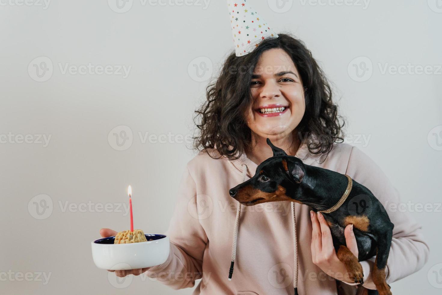 niña feliz dando pastel casero a su perro, en el interior foto