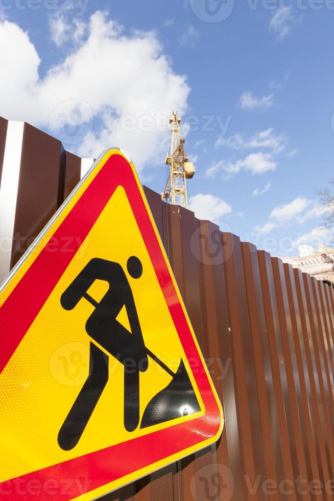 road sign for repairs installed on a metal fence photo