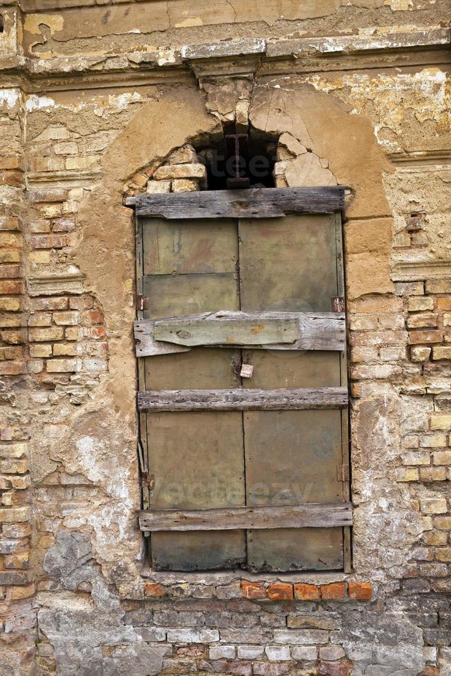 the window closed by boards which is on the ancient collapsing building. photo