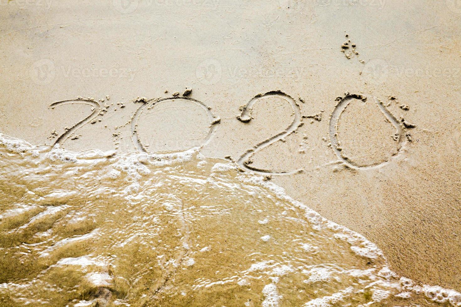 sea waves erasing the inscription of 2020 photo