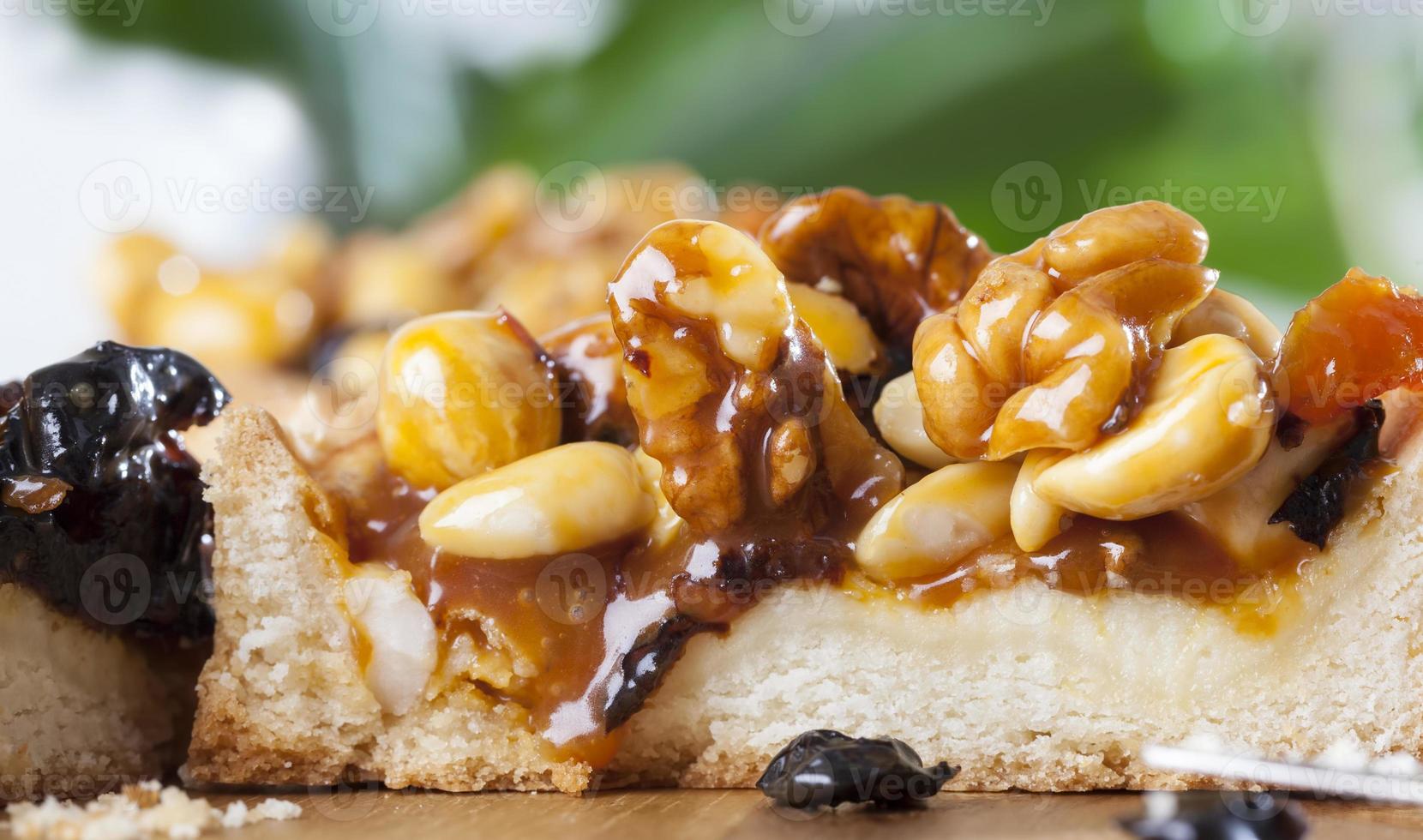 round tartlet with nuts and dried fruits poured with caramel photo