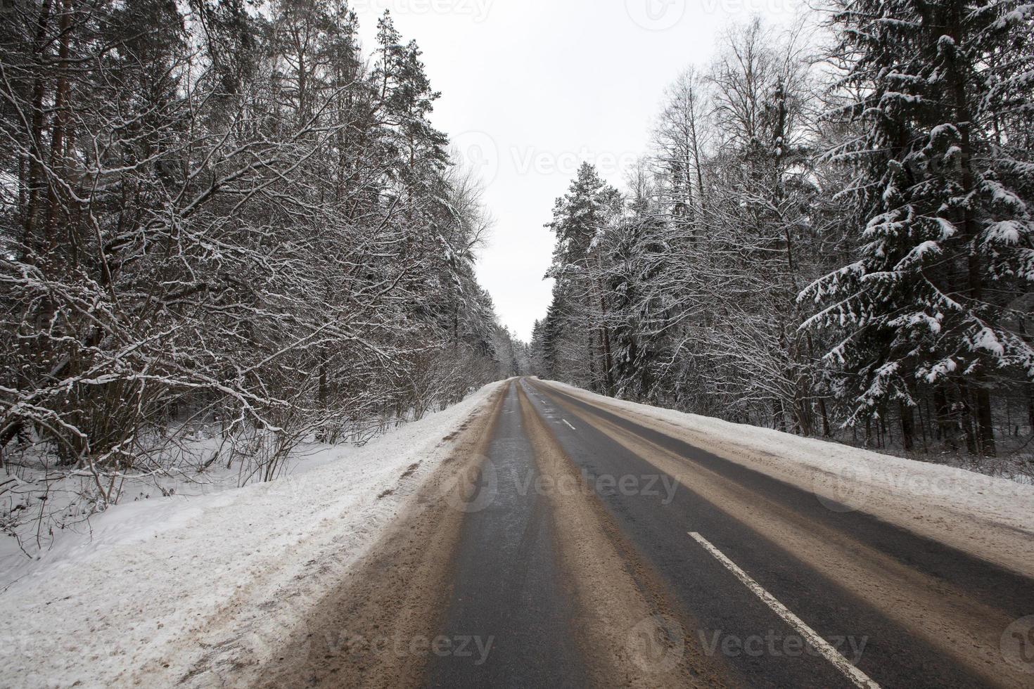 the road in the winter season, the roadway is covered with melted snow photo