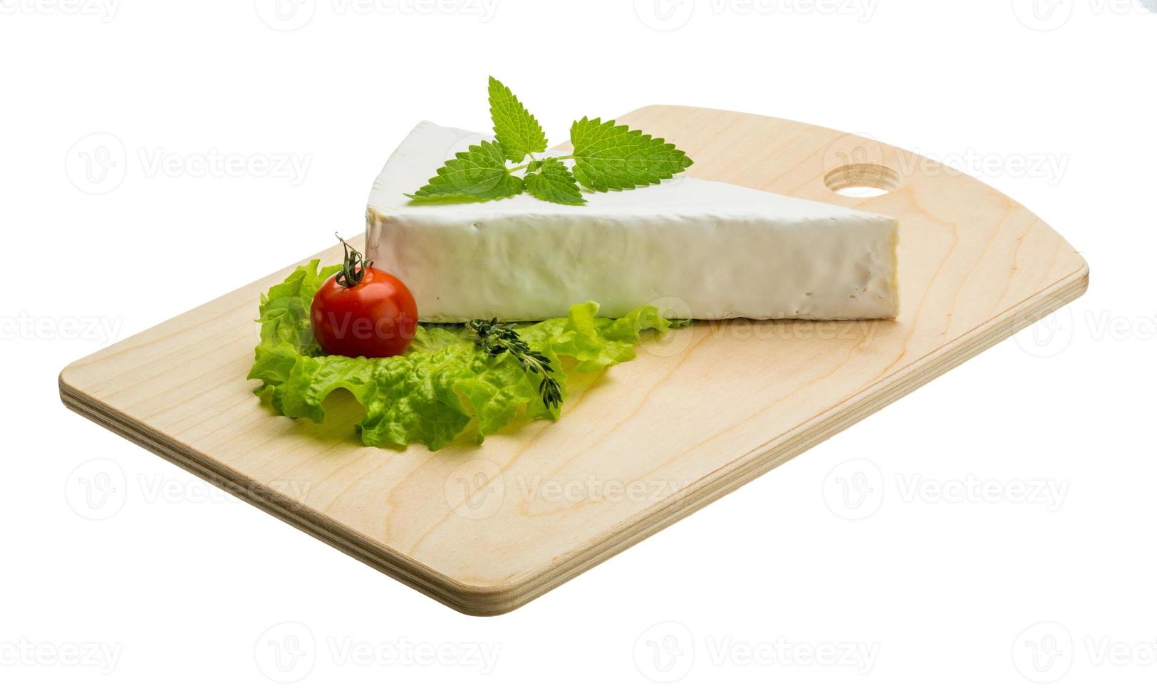 Brie cheese with thyme on wooden plate and white background photo