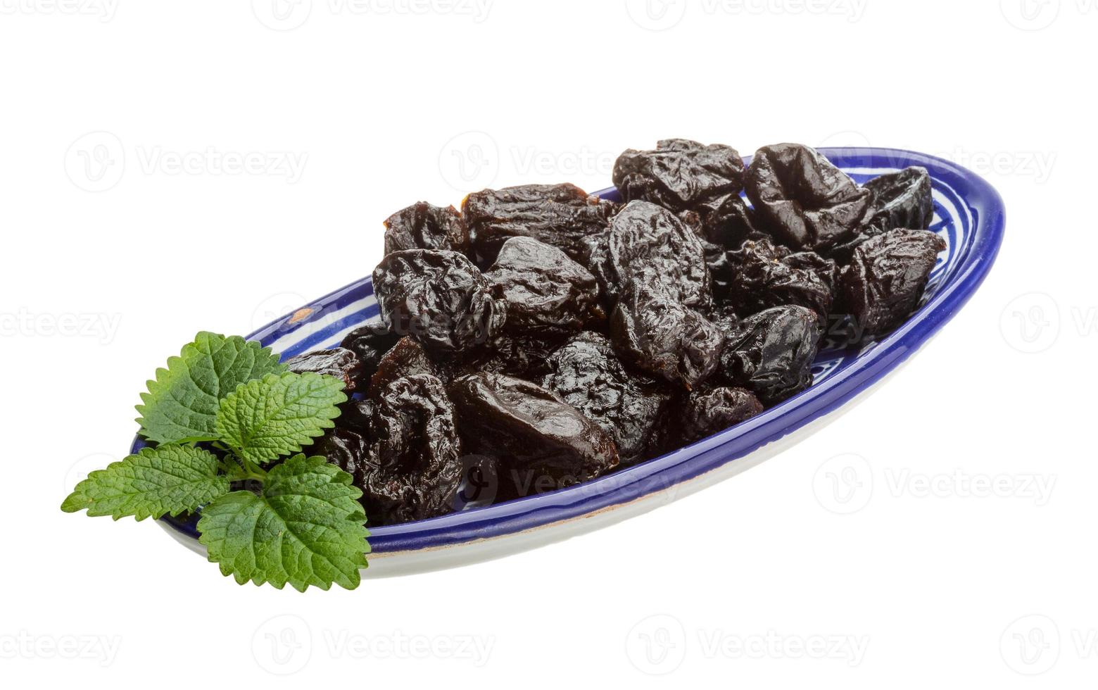 Dried plums in a bowl on white background photo