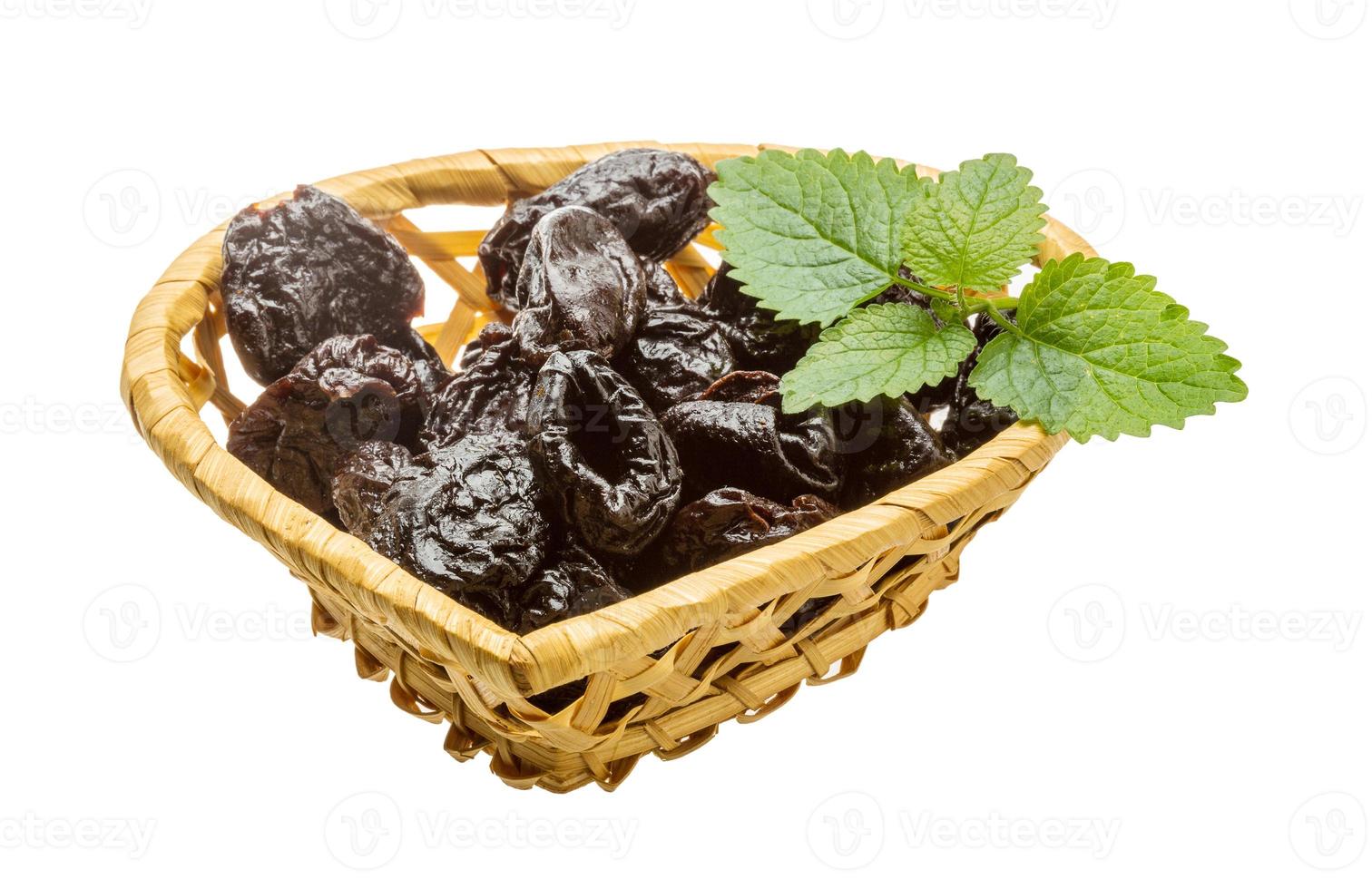 Dried plums in a basket on white background photo