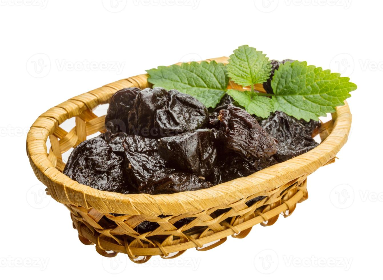 Dried plums in a basket on white background photo