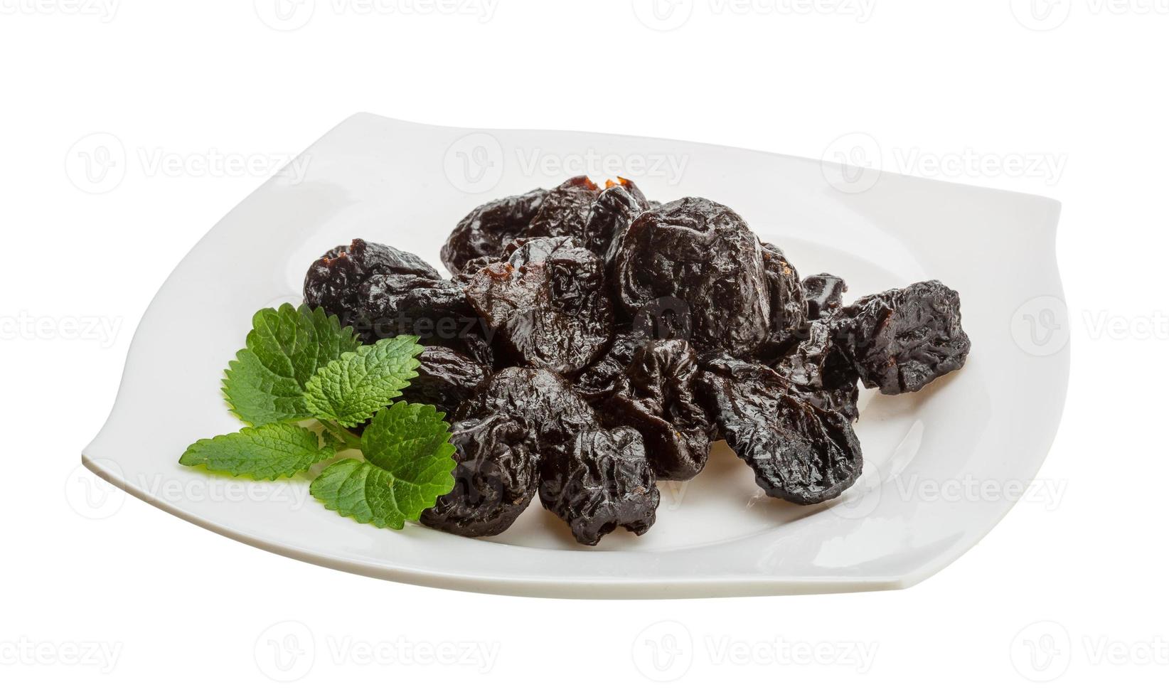 Dried plums on the plate and white background photo