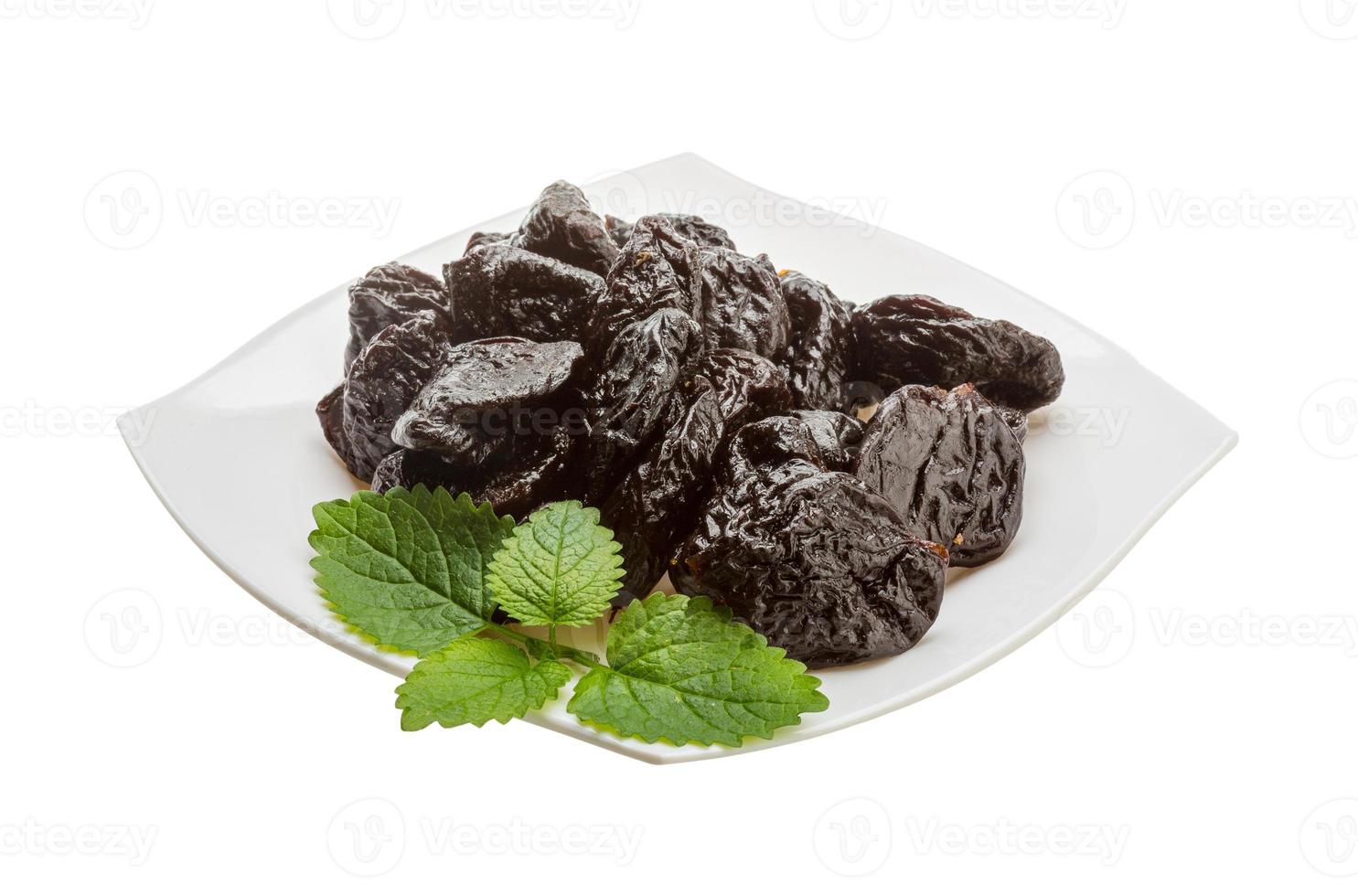 Dried plums on the plate and white background photo