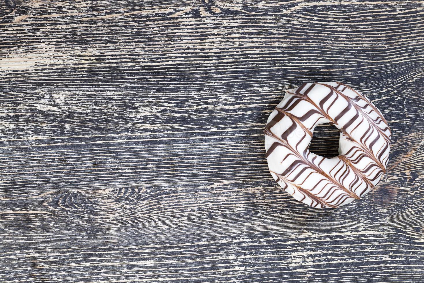 a fresh doughnut covered with white chocolate , closeup photo