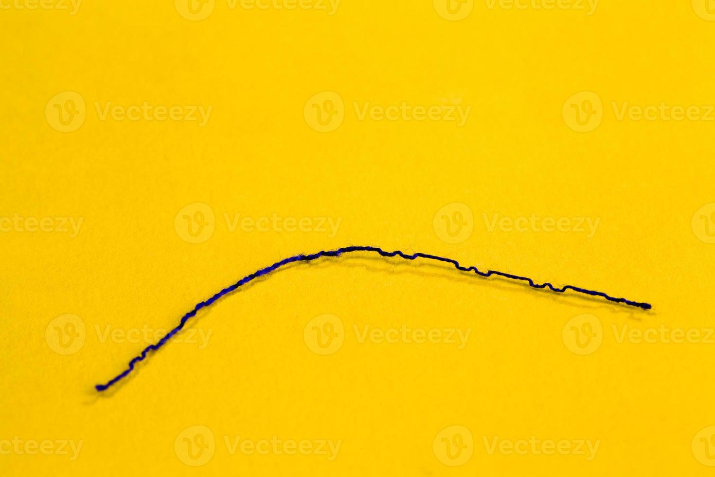 a thin black thread lies on the yellow paper photo