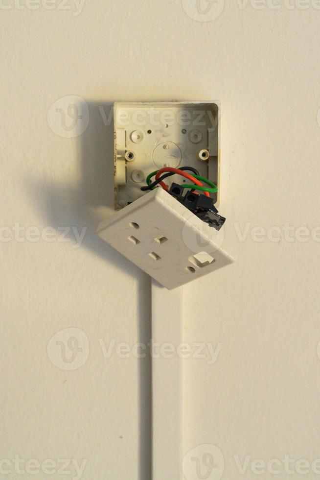 Broken electrical plug on the wall. photo