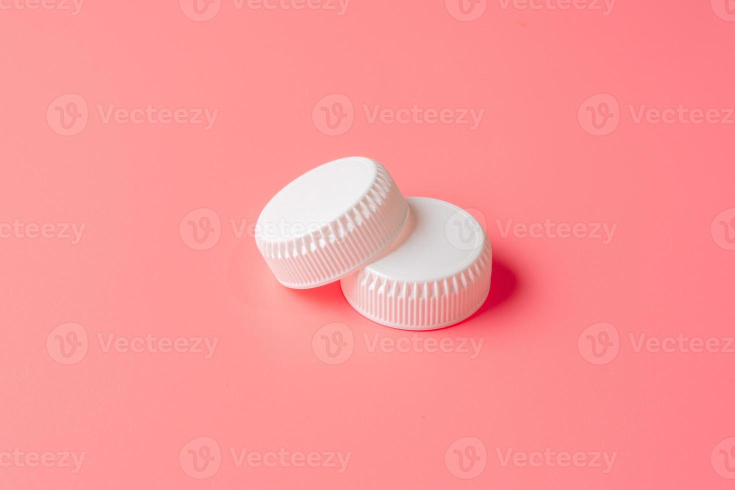 White bottles cap on light pink background. photo