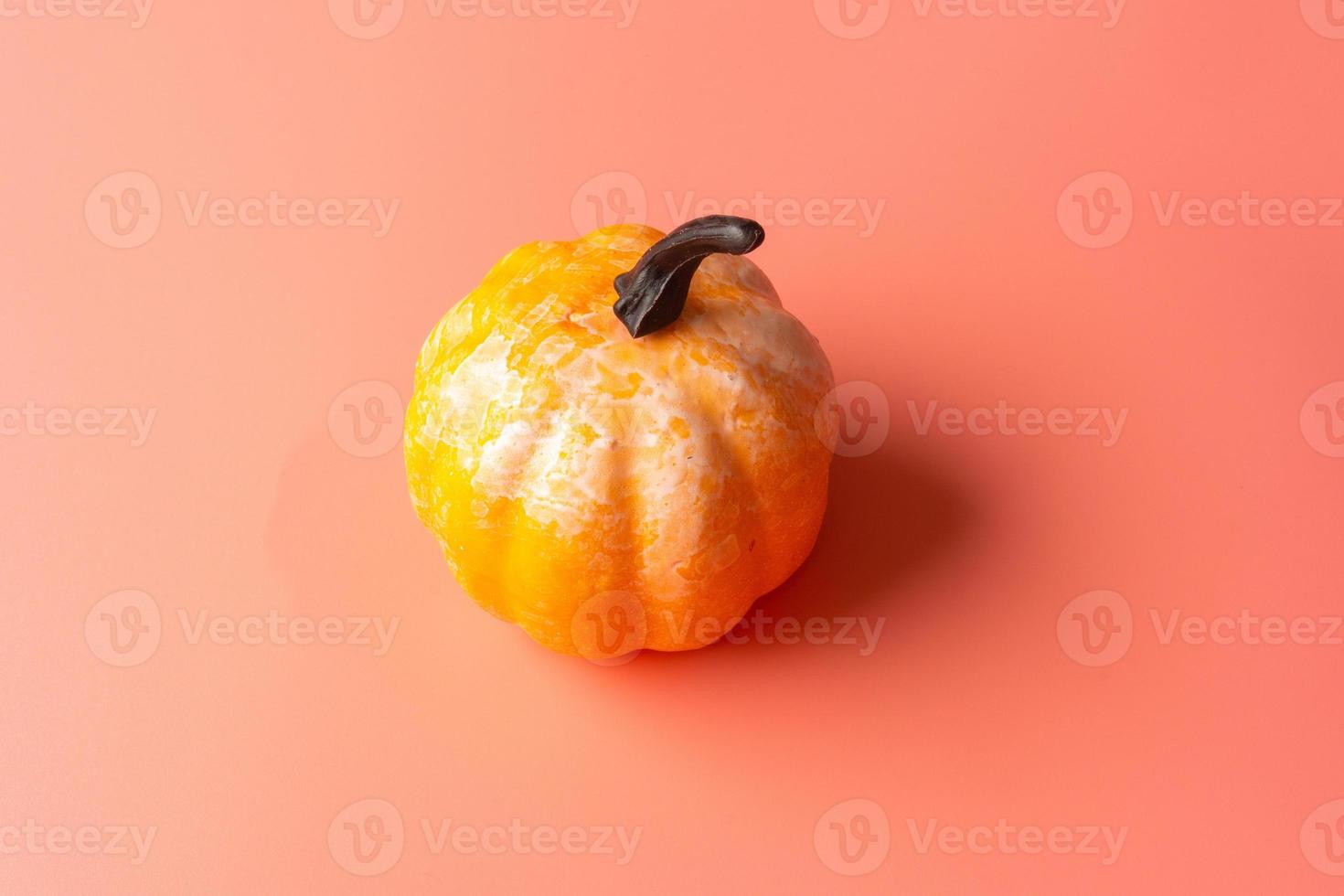 Artificial pumpkin on a light pink background. photo