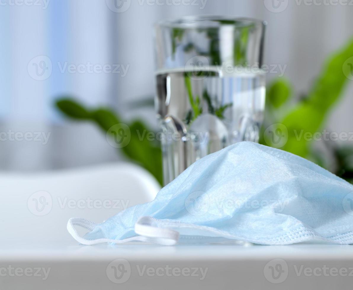 a clear glass cup and medical mask photo