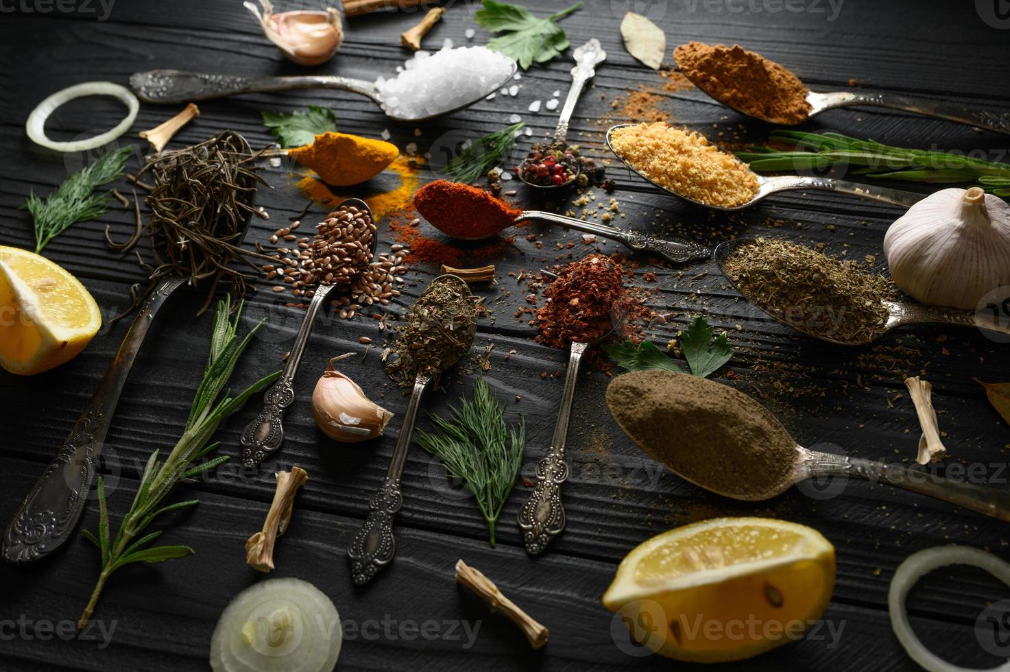 Colorful various herbs and spices for cooking on dark wooden rustic background photo