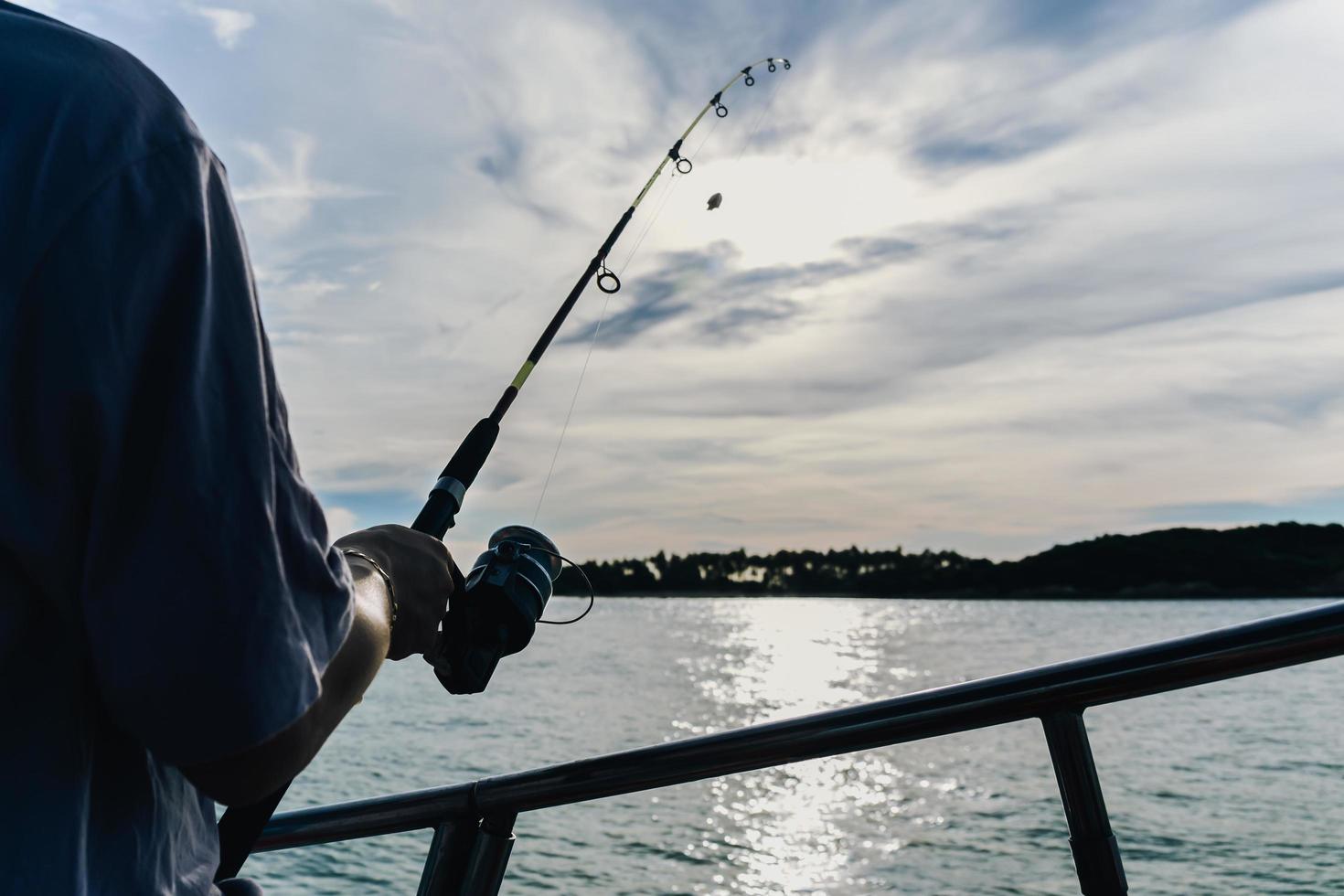 Fishing rod wheel closeup, man fishing with a beautiful sunrise. photo