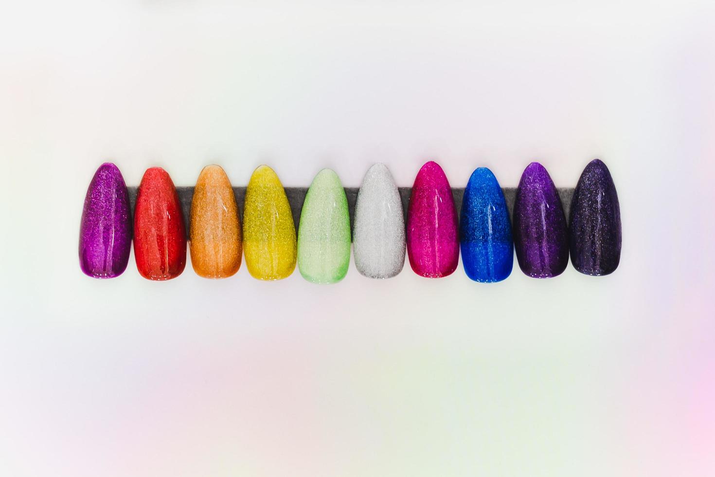 conjunto de uñas artificiales con coloridas muestras de manicura aisladas en fondo blanco. foto