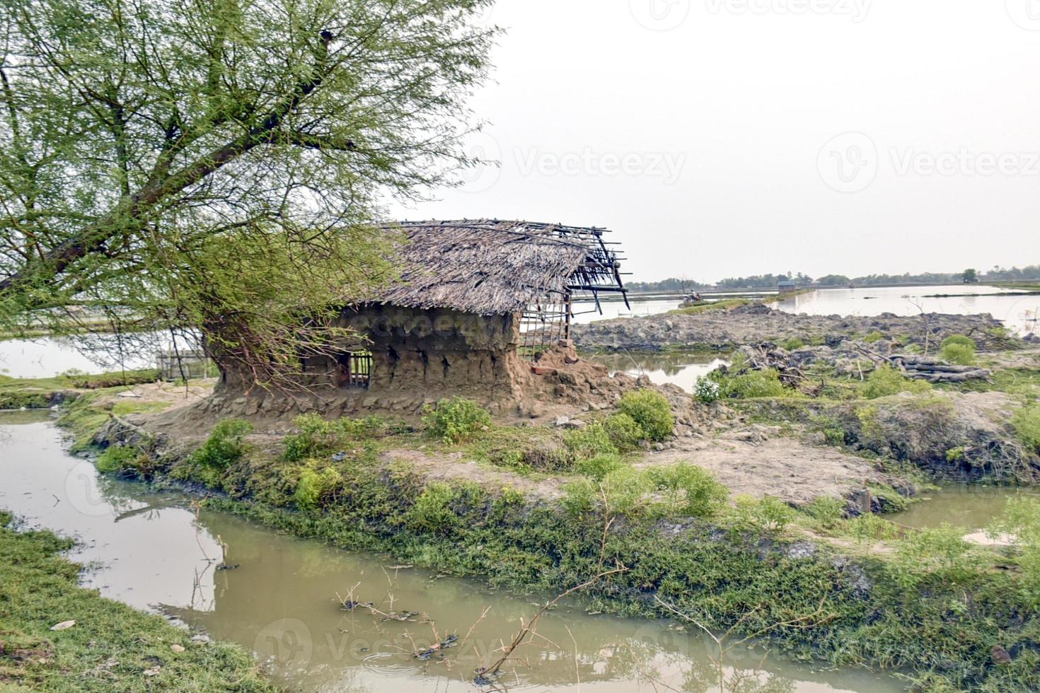 Abandoned old mud house with thatched roof collapsed after a cyclone in the countryside. Side view of a damaged clay house. photo