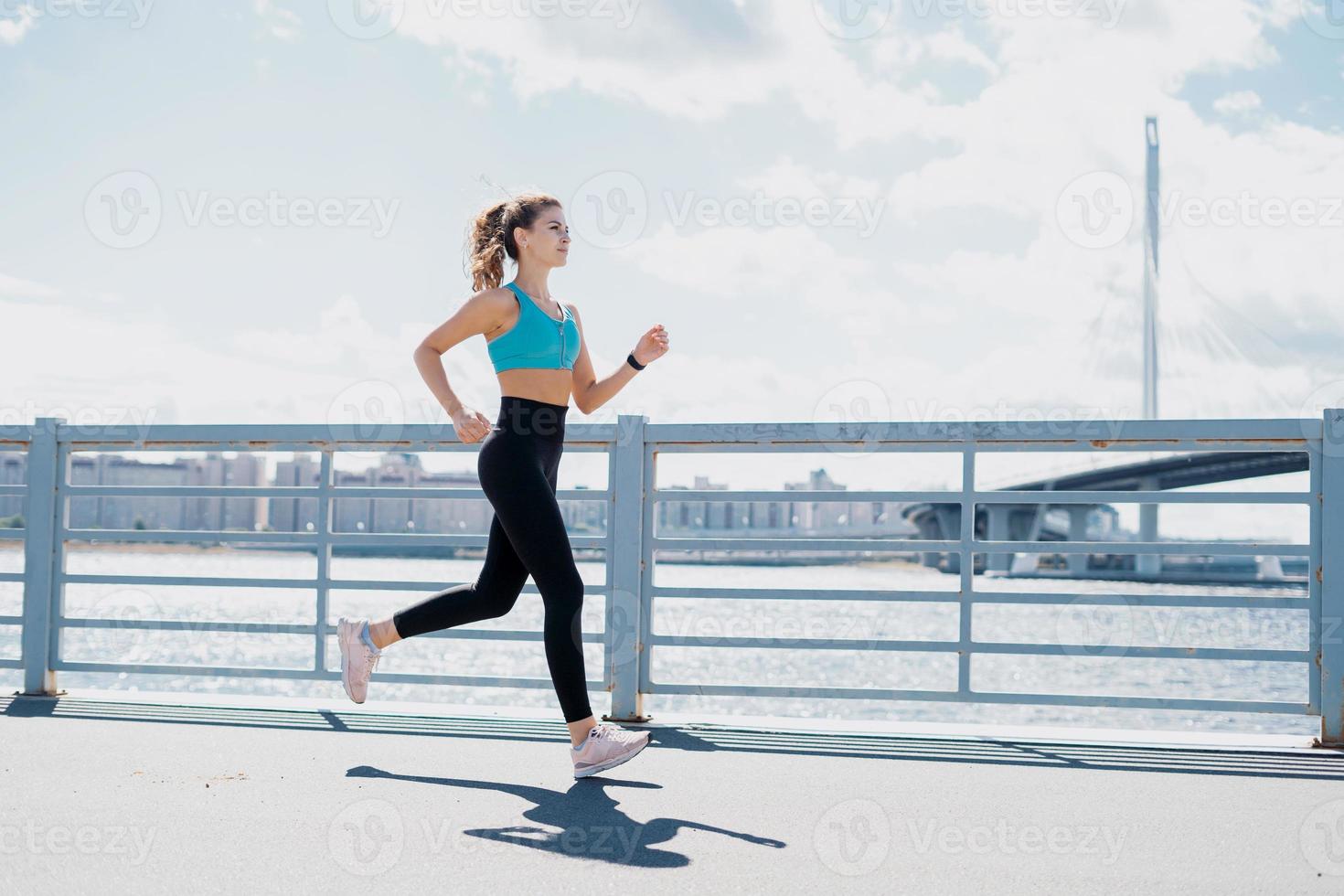 A confident female running coach does strength exercises in the open air. Healthy lifestyle concept. Slim figure and comfortable shoes. photo