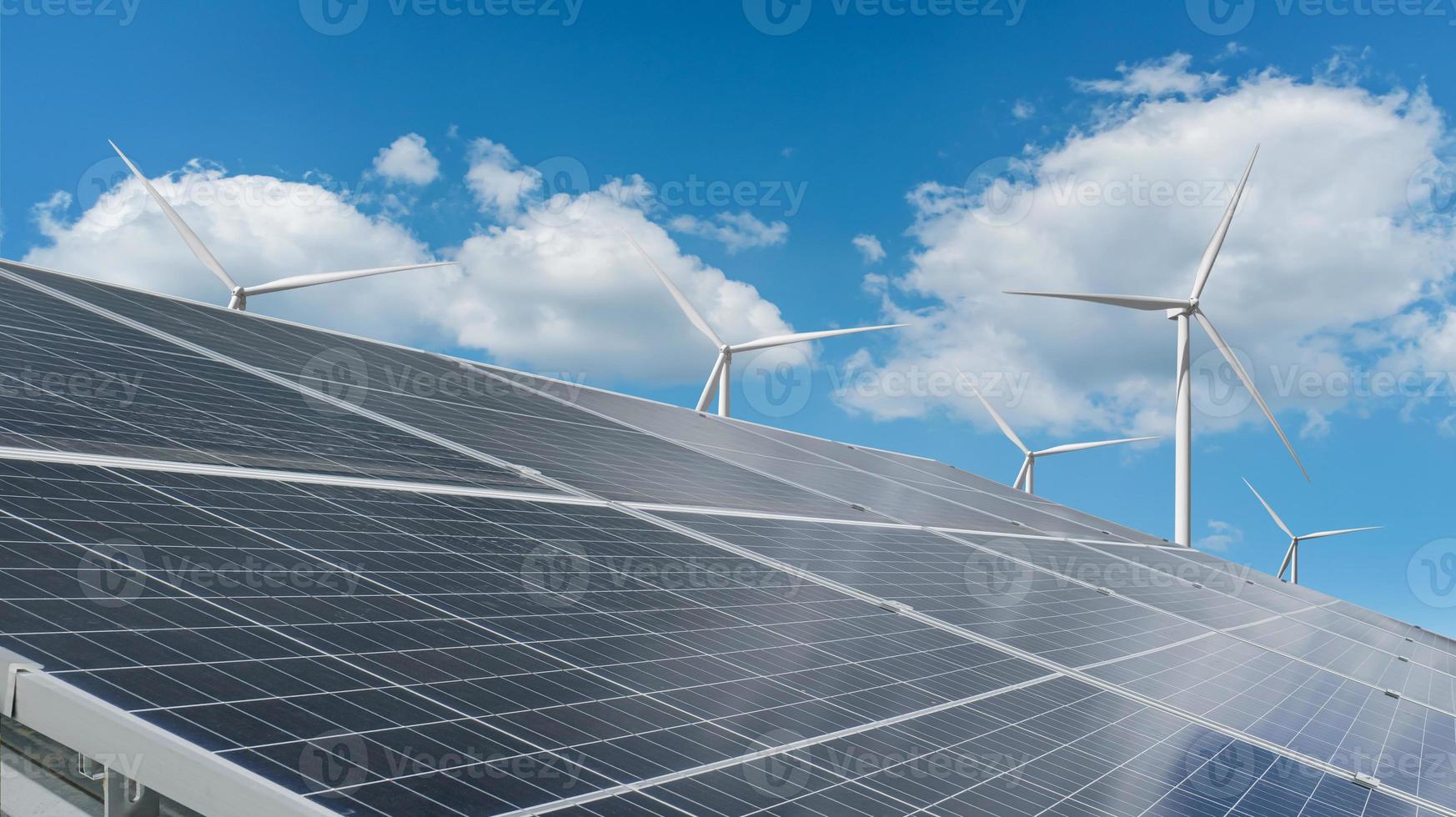 Solar module panels with wind turbine against blue sky background. Environmental energy resources concept. photo