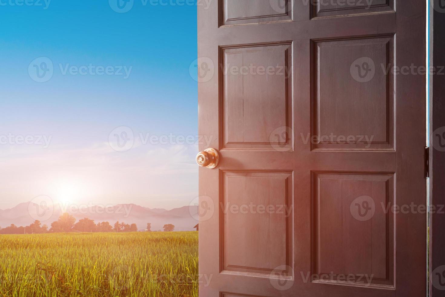 open door with a view of green meadow field at sunrise sky background. photo