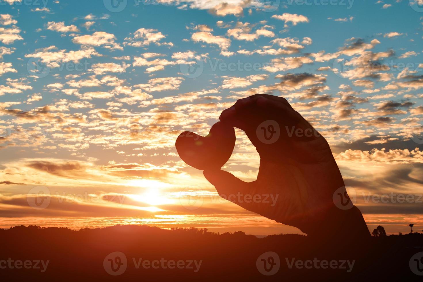 Silhouette of hands holding hearts on sunset sky background. love day concept photo