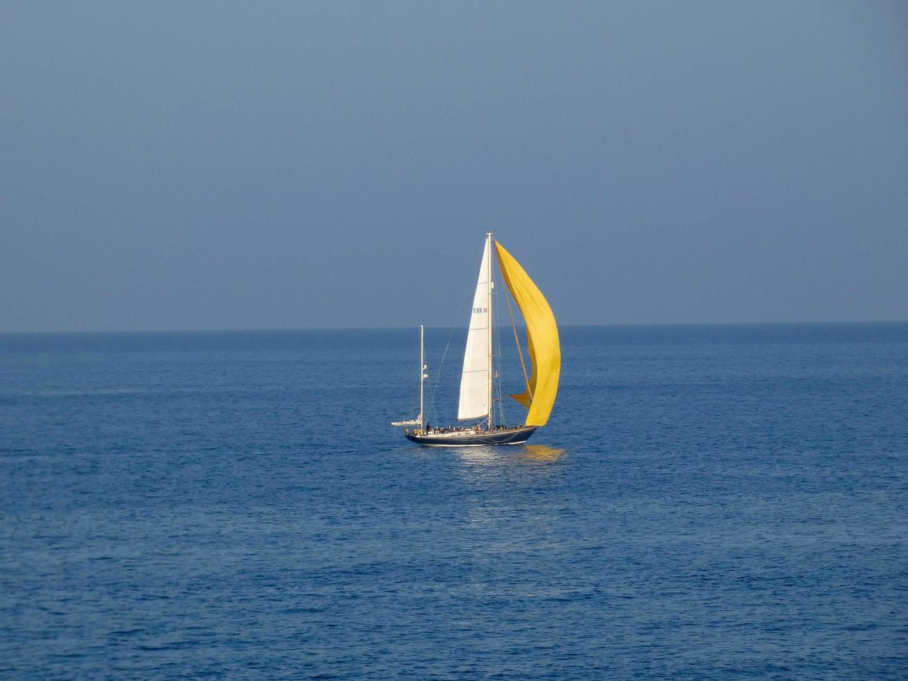 Sport sailboat sailing with sails unfurled on a blue sea photo