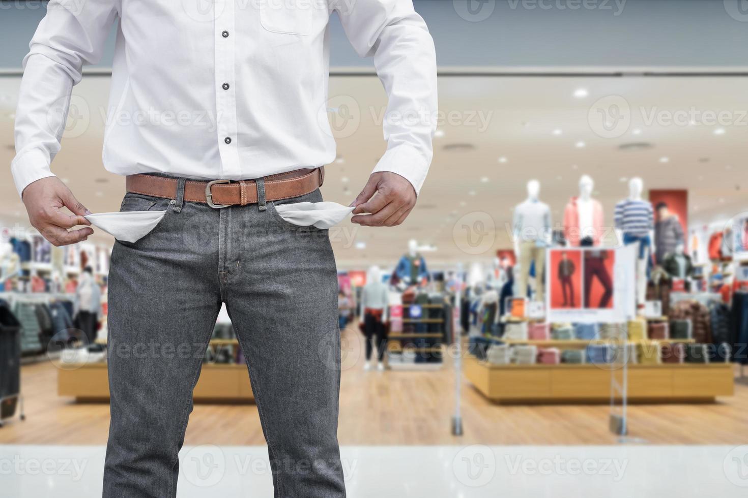 Man showing his empty pockets on blur shopping mall photo