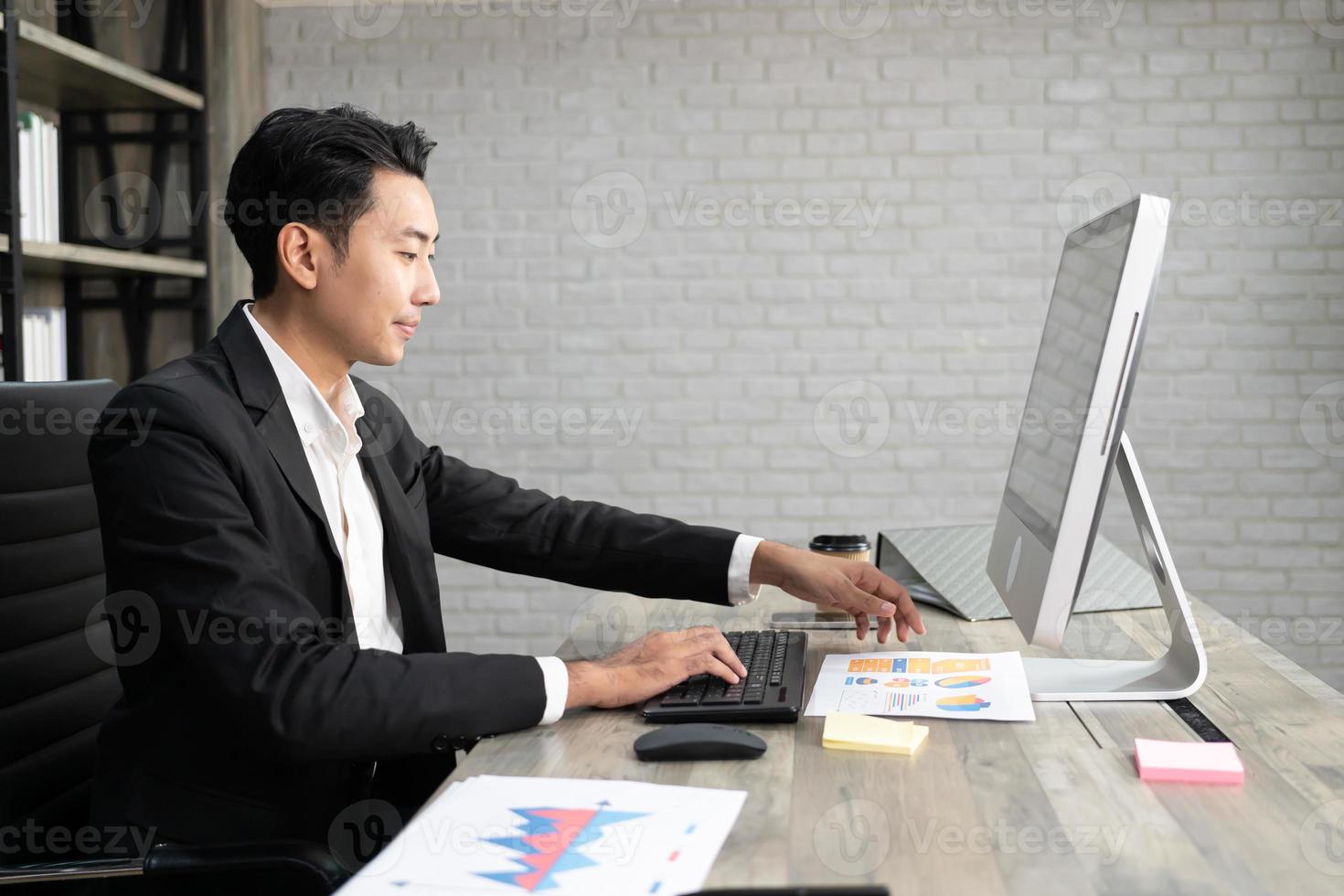 retrato de hombre de negocios usando computadora en el lugar de trabajo en una oficina. hombre de negocios positivo sonriendo mirando el papel. foto