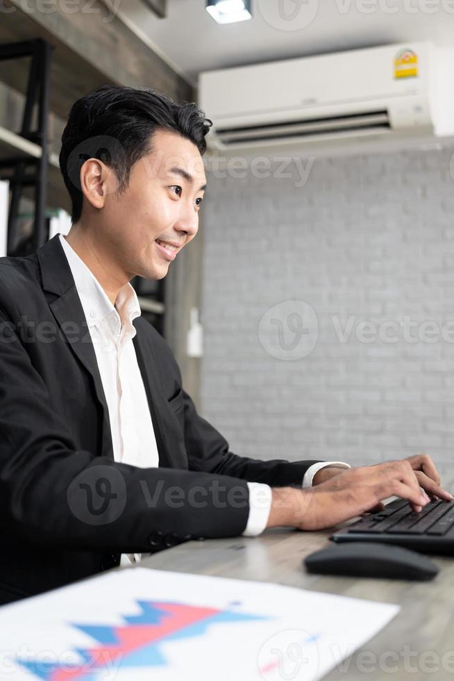 retrato de hombre de negocios usando computadora en el lugar de trabajo en una oficina. hombre de negocios positivo sonriendo mirando a la pantalla de la computadora. foto