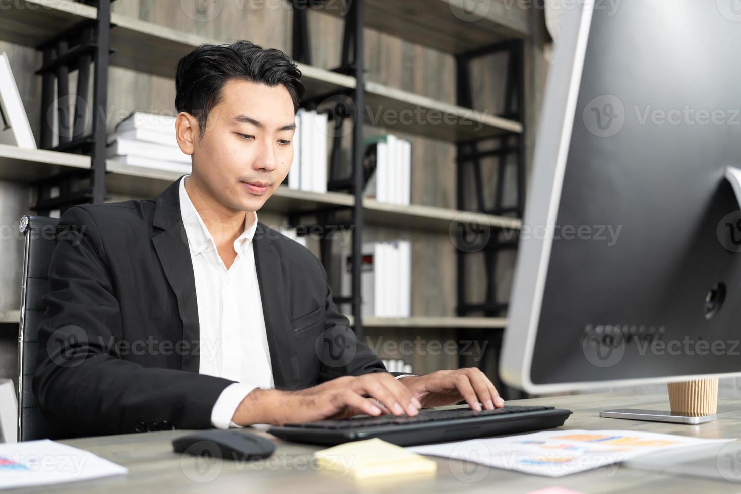 retrato de hombre de negocios usando computadora en el lugar de trabajo en una oficina. hombre de negocios positivo sonriendo mirando a la pantalla de la computadora. foto