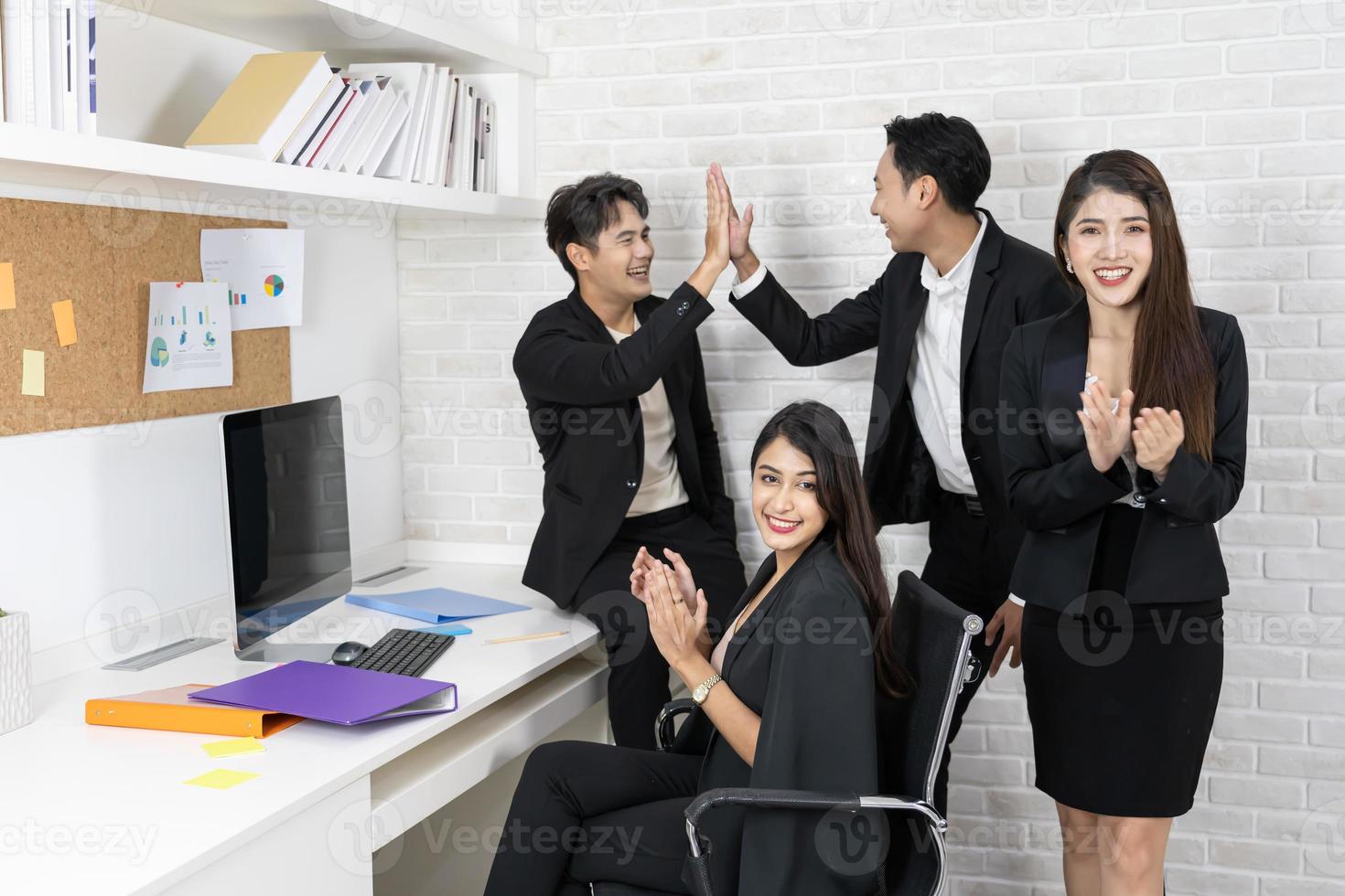 equipo de negocios feliz aplaudiendo. gente de negocios trabajando juntos en proyectos y lluvia de ideas en la oficina. amables empleados diversos felicitando a la mujer de negocios por los logros empresariales. foto