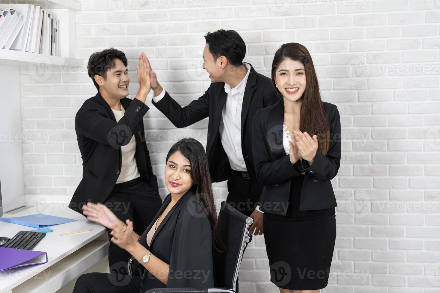 Happy business team applauding. Business people working together on project and brainstorming in office. Friendly diverse employees congratulating businesswoman with business achievement. photo