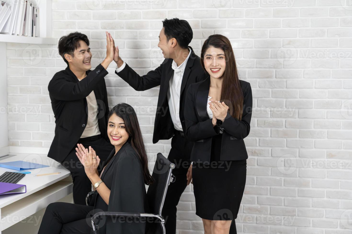 equipo de negocios feliz aplaudiendo. gente de negocios trabajando juntos en proyectos y lluvia de ideas en la oficina. amables empleados diversos felicitando a la mujer de negocios por los logros empresariales. foto