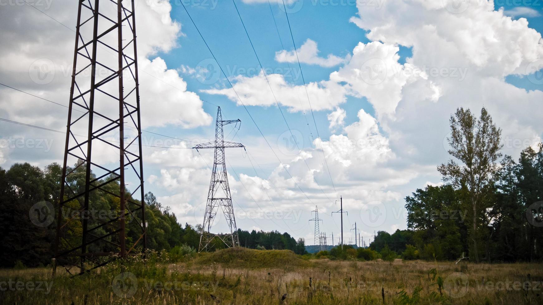 Wide shot timelapse of electricity power lines and high voltage pylons on a field in the countryside at summer. photo