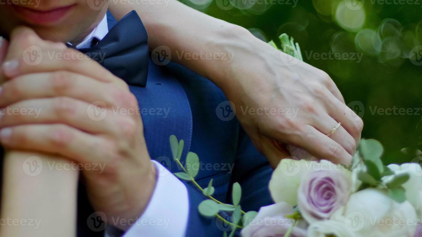 Beautiful bride and groom are kissing in a sunny park, close up photo